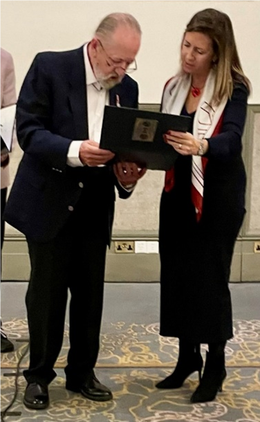 A person and person holding a folderDescription automatically generated