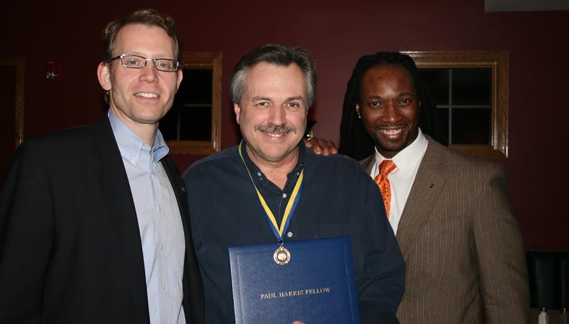 Rotarian Kevin Crosby (center) receives a Paul Harris Fellowship award.