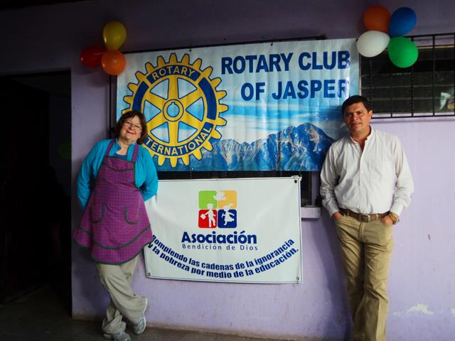 A person and person standing in front of a bannerDescription automatically generated