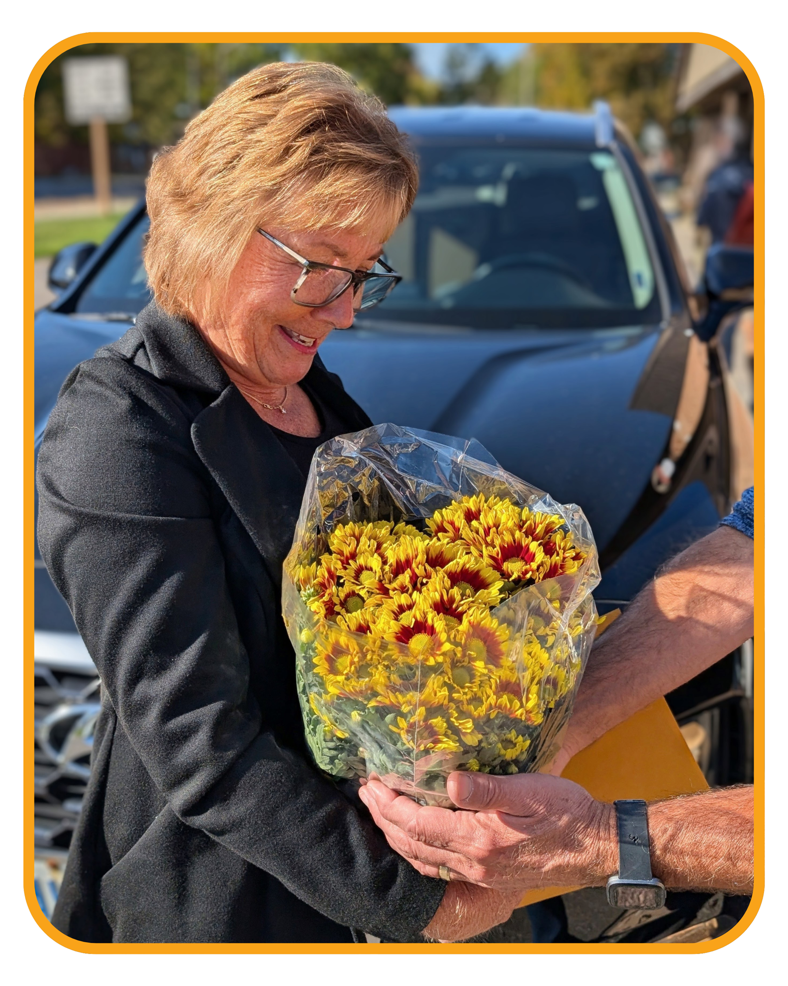 A woman receiving a Thanksgiving mum.