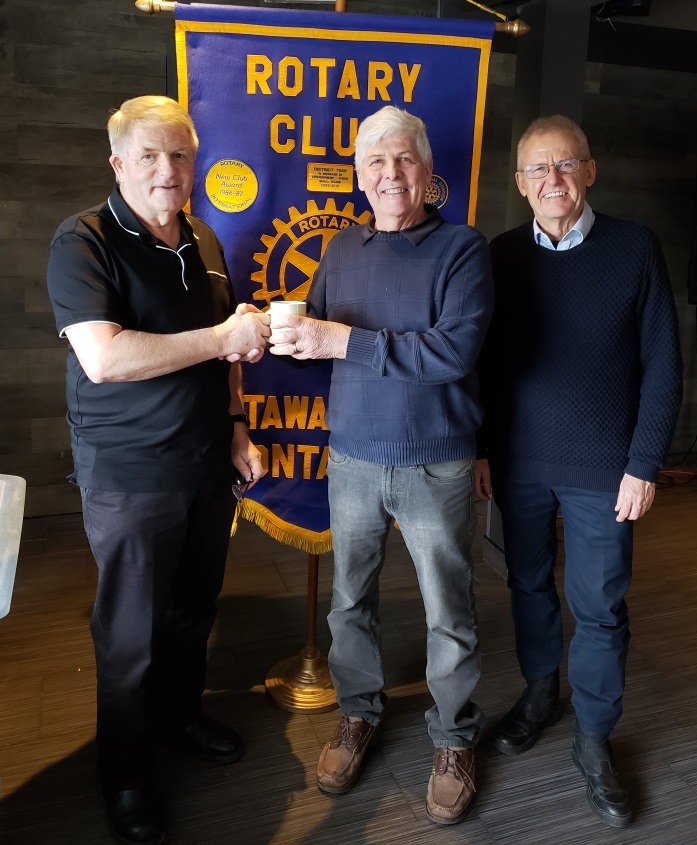 Gary Pluim and Alex Davidson from the Rotary Club of Ottawa South flank Master Electrician Earle Clarke.