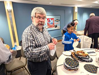 A person standing next to a table with plates of foodDescription automatically generated