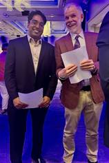 Two men holding papers in their handsDescription automatically generated