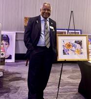 A person in a suit standing in front of a picture frameDescription automatically generated