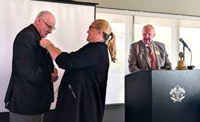A person putting a tie on a personDescription automatically generated