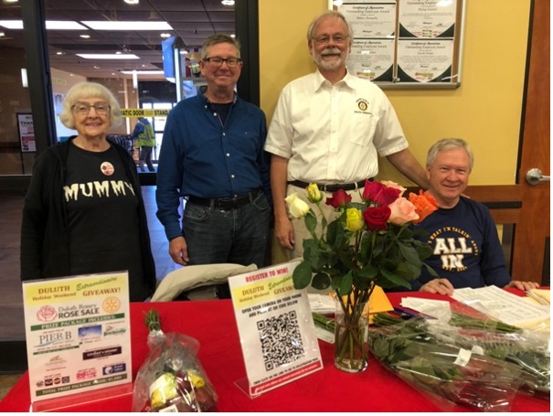 A group of people standing next to a table with flowersDescription automatically generated