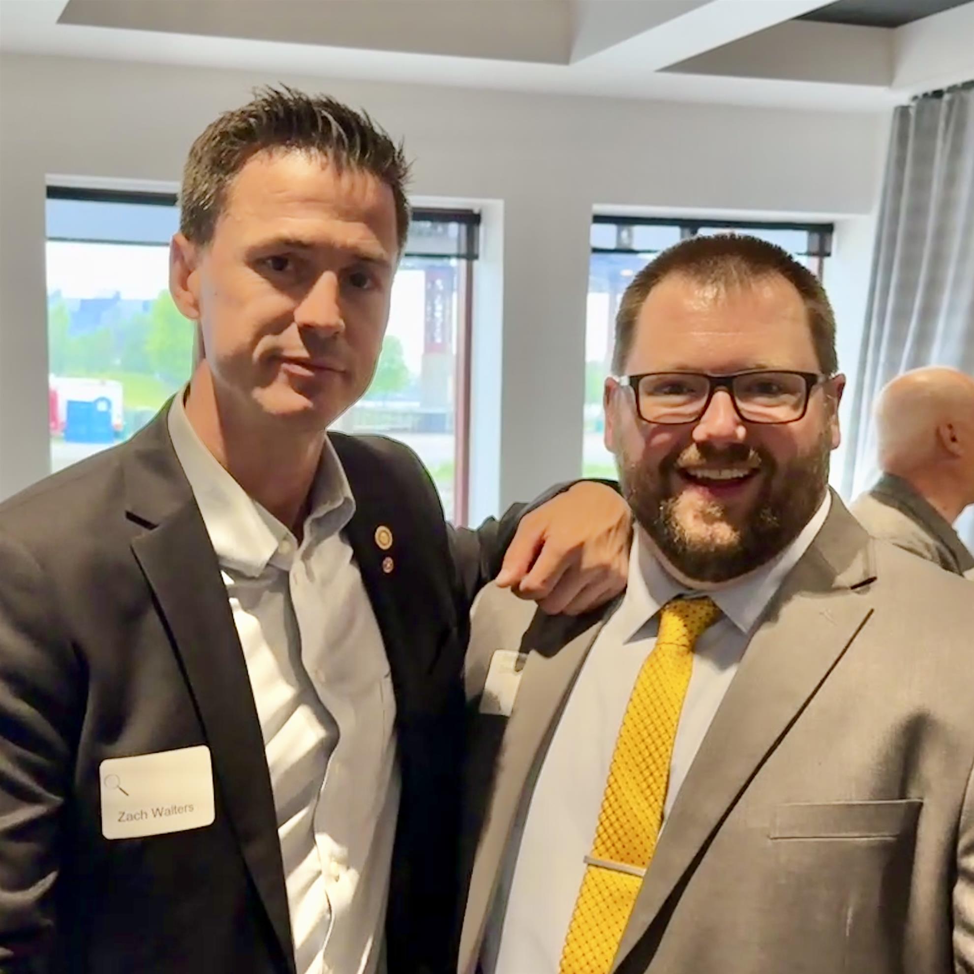 Two men in suits posing for a pictureAI-generated content may be incorrect.