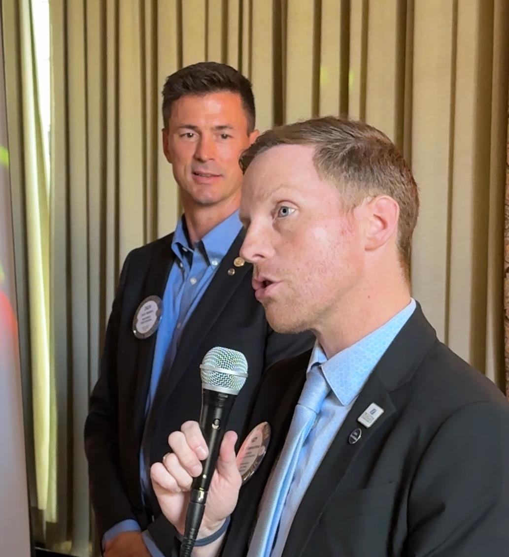 A person in a suit holding a microphoneAI-generated content may be incorrect.