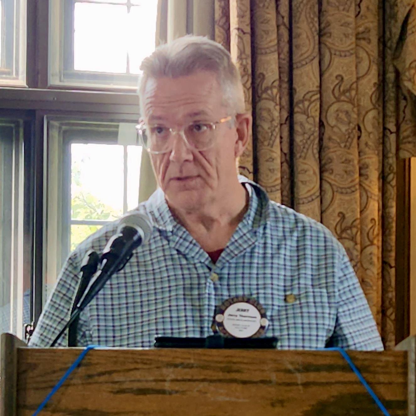 A person standing at a podium with a microphoneAI-generated content may be incorrect.