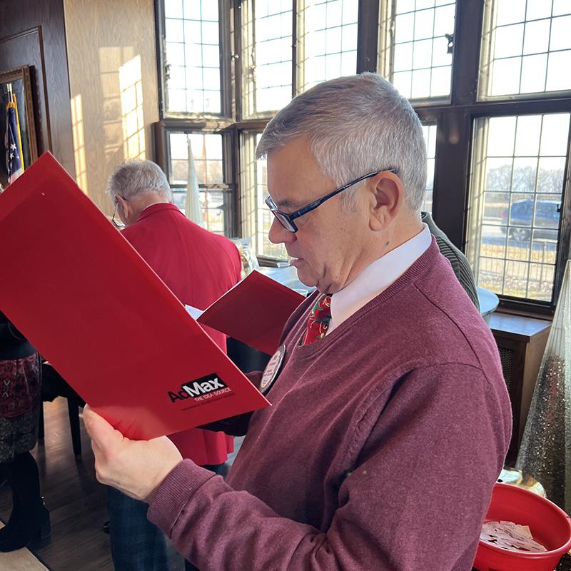 A person holding a red folderDescription automatically generated