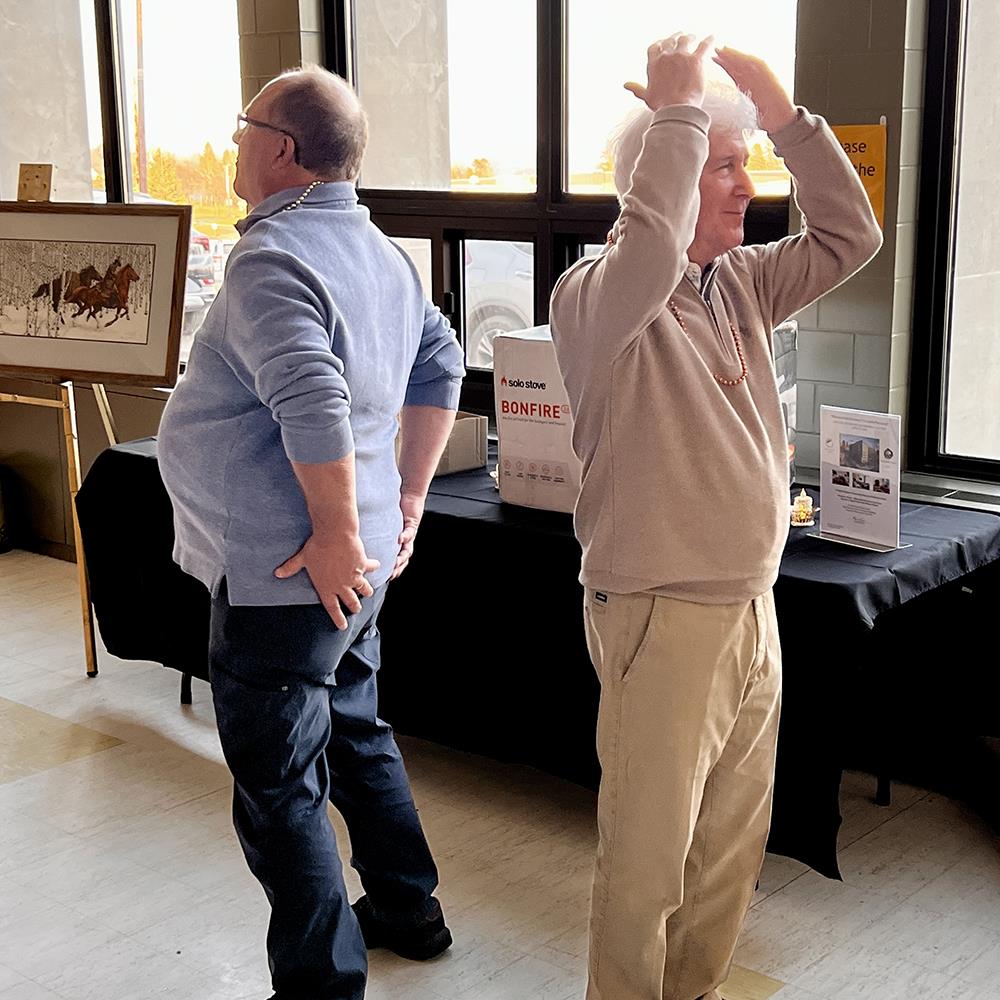 Two men standing in a roomDescription automatically generated