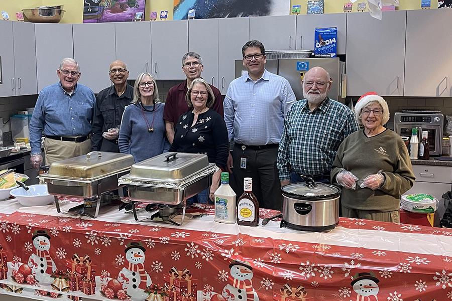 A group of people standing in front of a table with foodDescription automatically generated