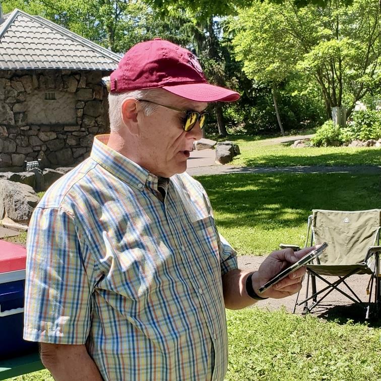 A person in a red hat and sunglasses looking at a cell phoneAI-generated content may be incorrect.