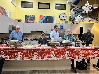A group of people standing around a table with foodDescription automatically generated