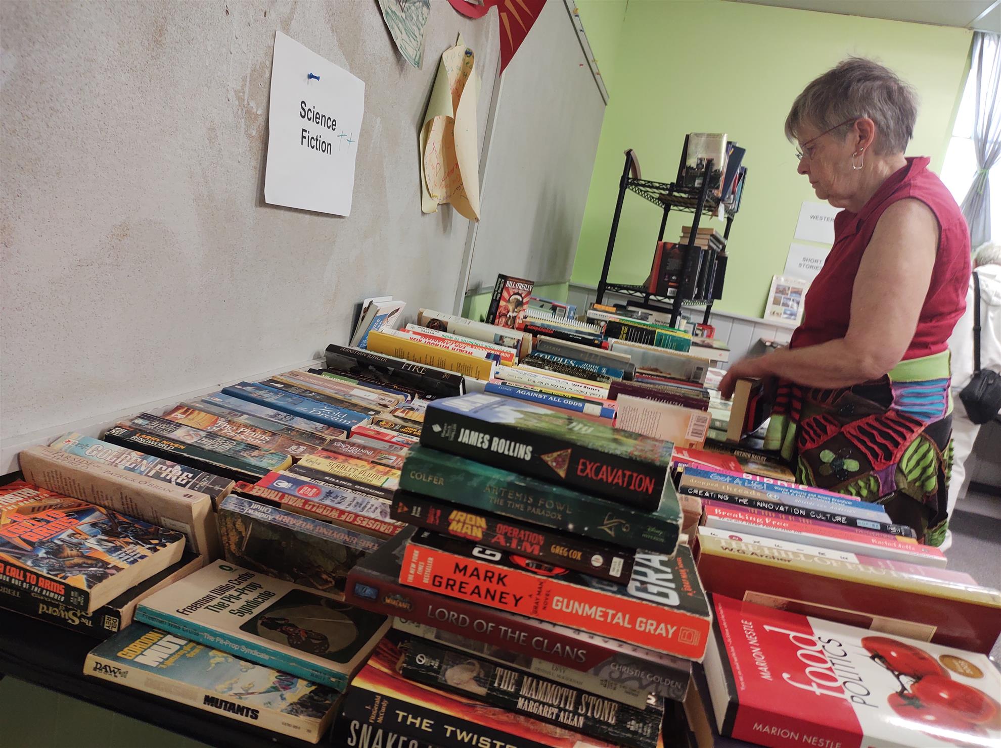 A shopper browses a table of used Sci-Fi books.