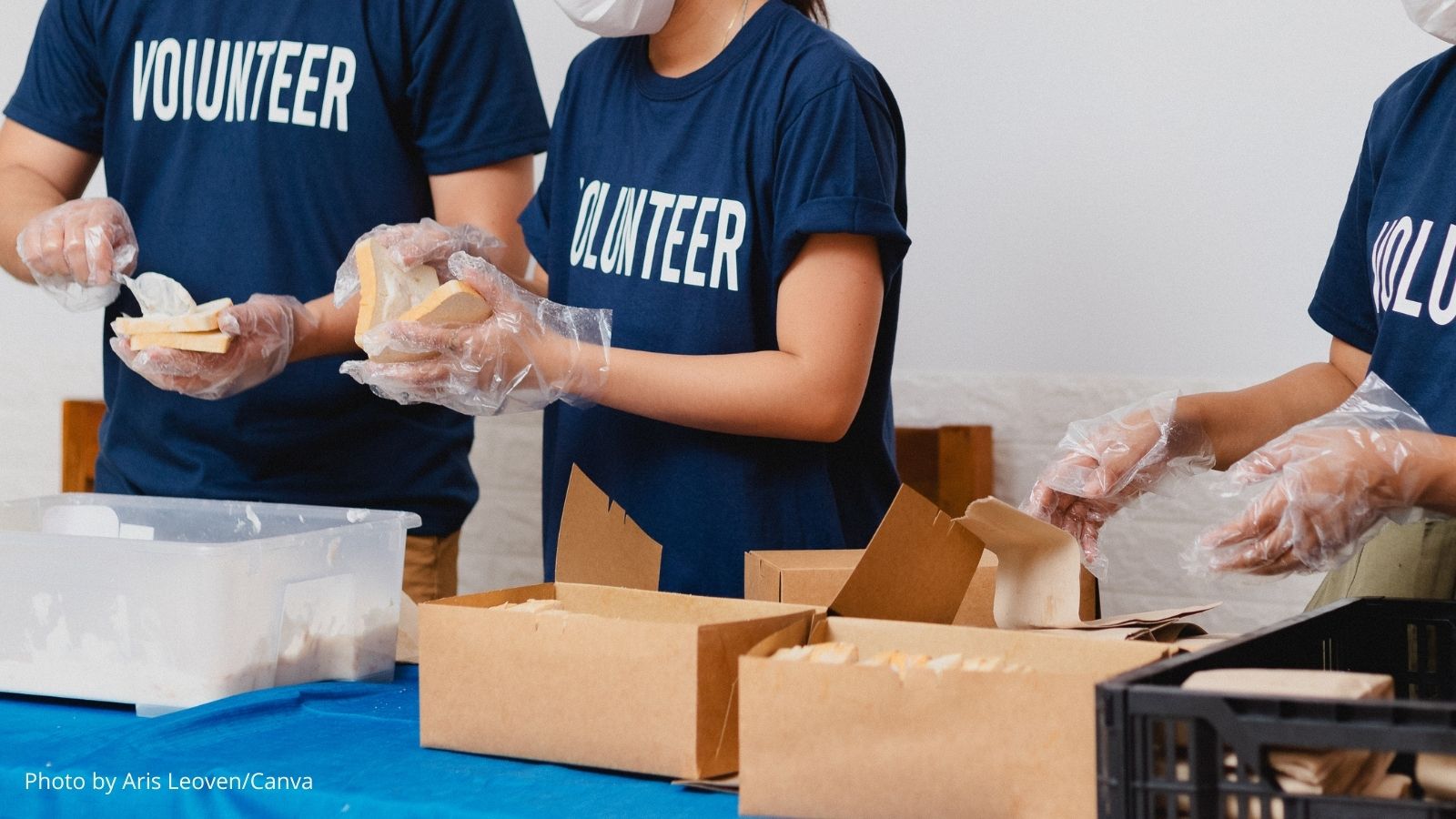 A photo of volunteers making sandwiches and putting them in boxed lunch kits.