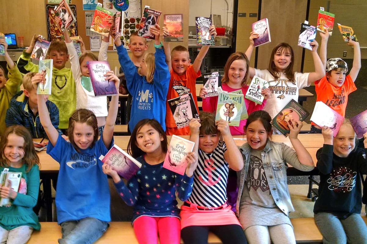 second grade students holding up their new books
