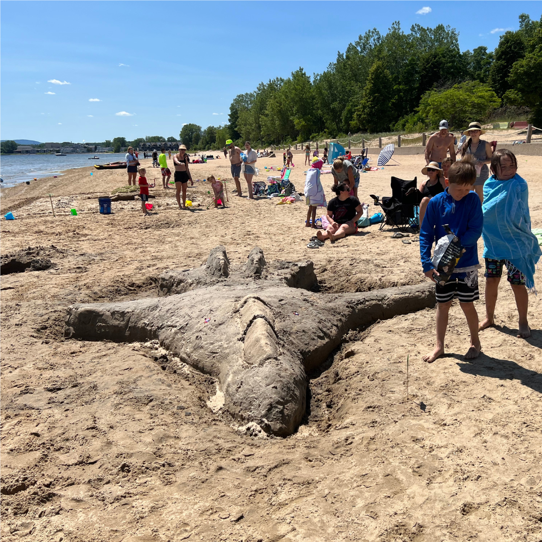 Photo of beach with sand sculpture and children