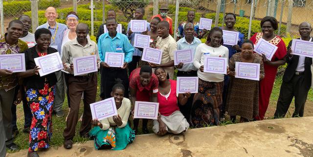 Gertrude Noden, her husband Drew, and a group of teachers in Uganda after attending a workshop on teaching life skills.