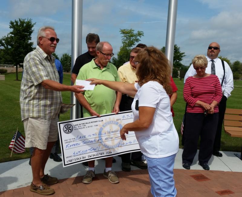 LITH Rotary Club President Dot Dustin presents the third of three $15,000 checks to Paul Mulcahy, Village President