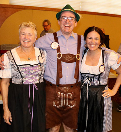 two women and one man in oktoberfest costumes and smiling