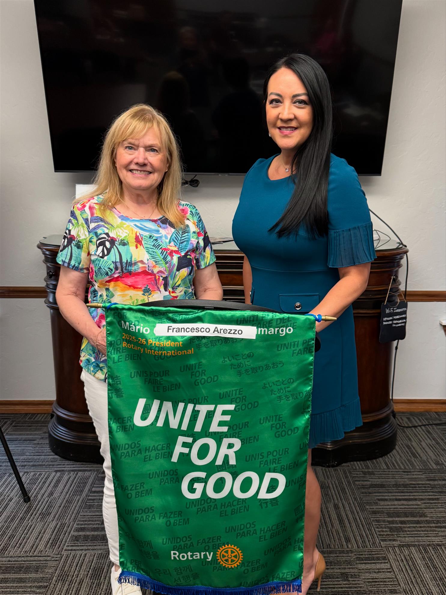 President, Aleta Wheelbarger and member Angie Clemens Mardis behind Rotary banner.
