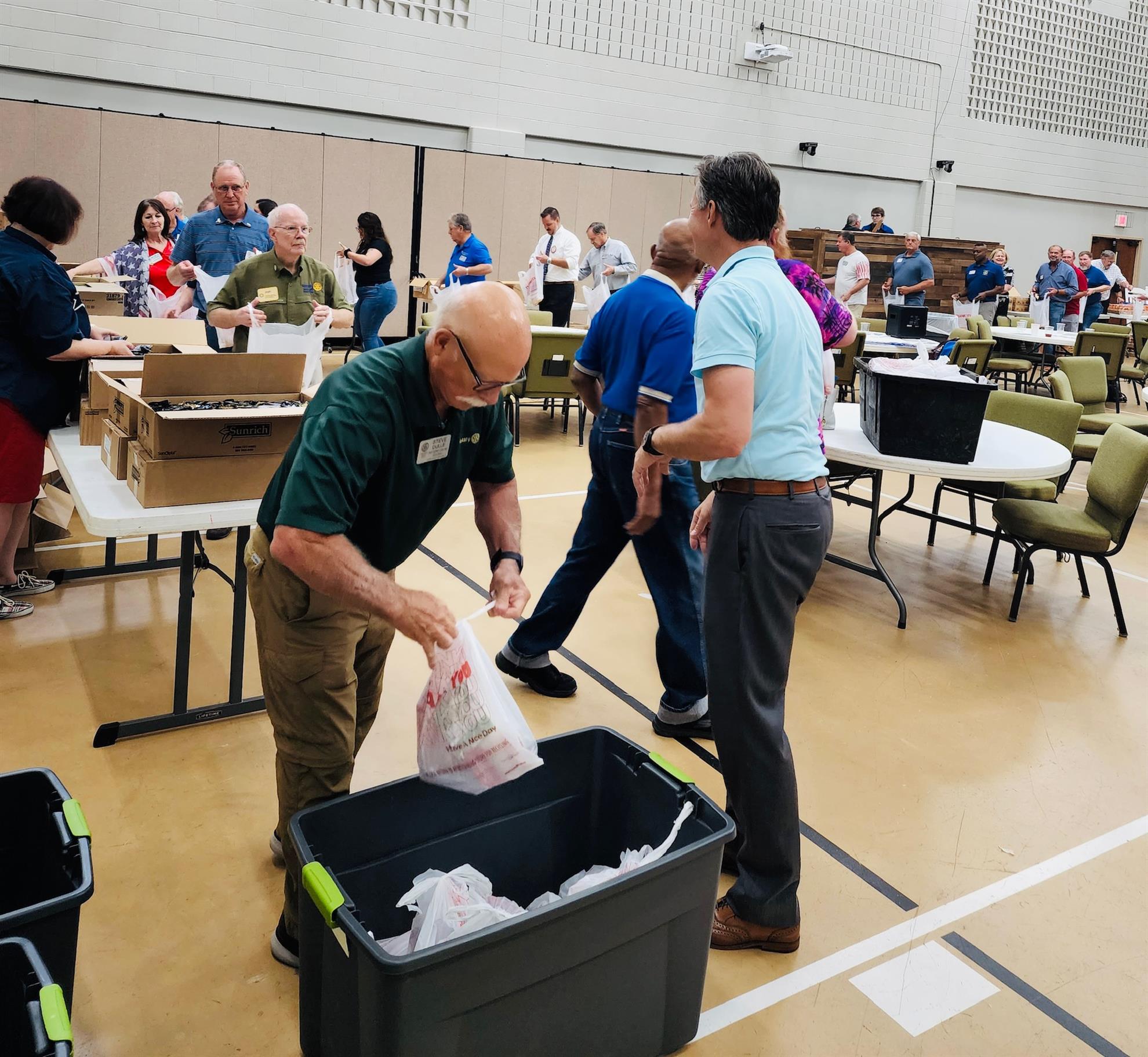 Rotarians form an assembly line to pack weekend food kits.