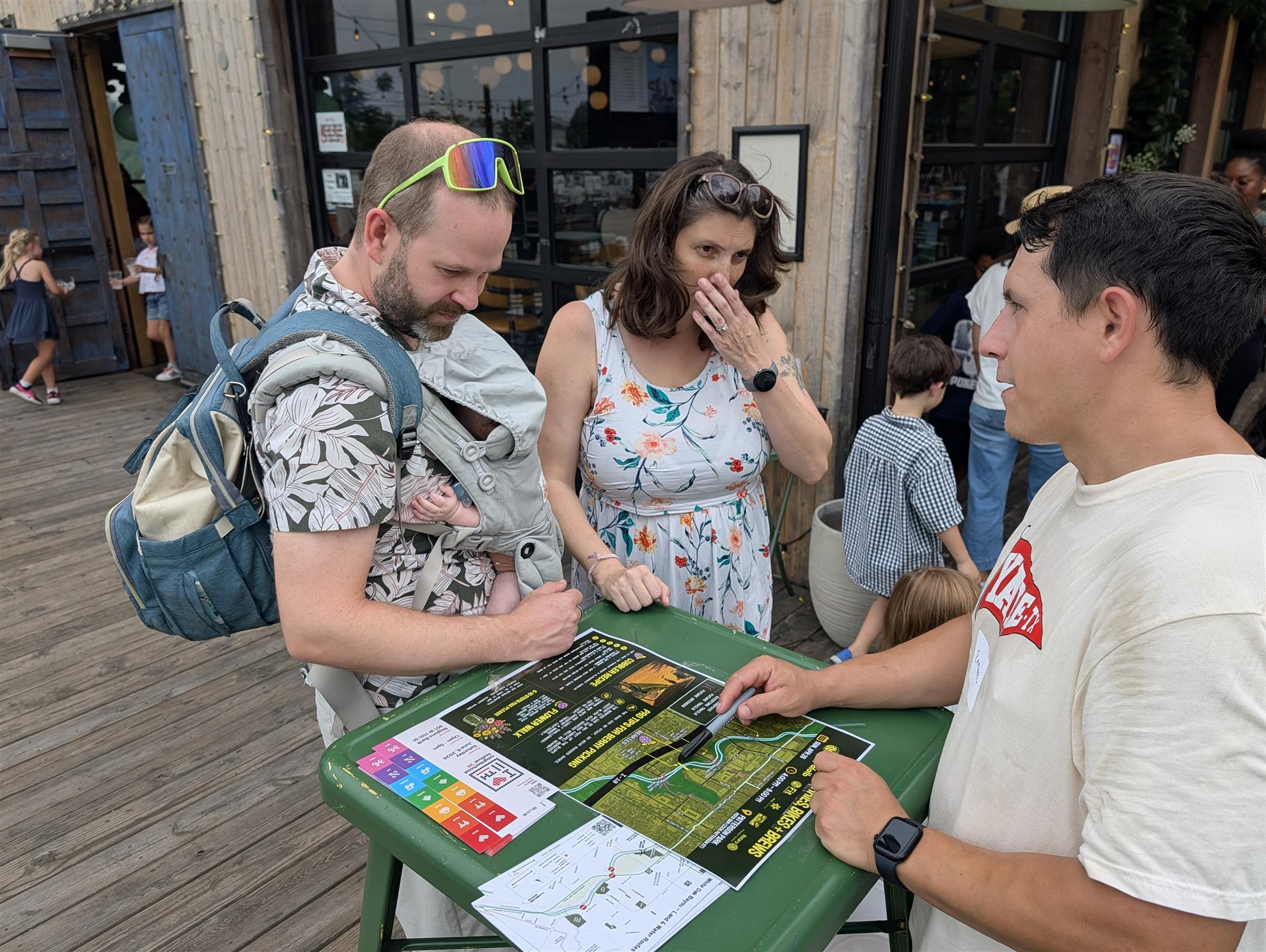 Emmanuel showing a couple and their infant the trail map, and where to find the dewberries and blackberries.
