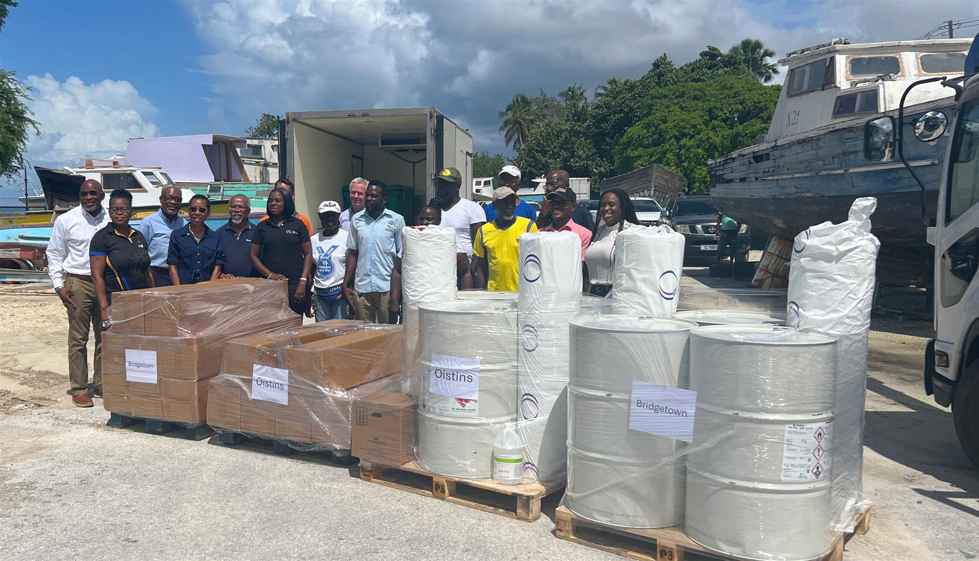 Image of supplies for fisherfolk.  Presidents, ADG Paul and the fisherfolk representatives standing behind the supplies