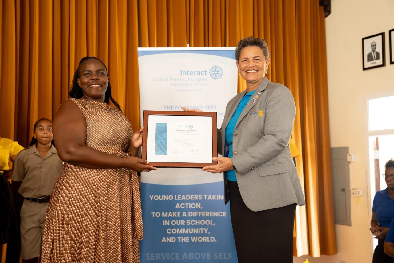 PDG Sonya presenting the charter certificate to Ma Greenidge