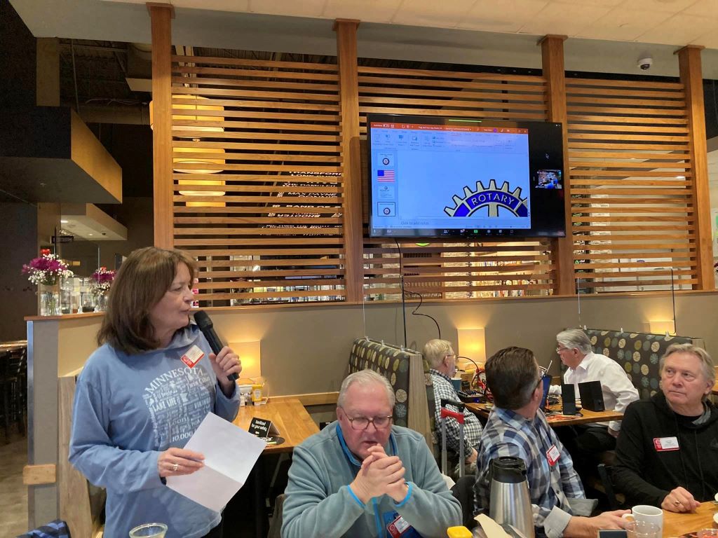 The president of the rotary club, Lisa Jacobson, speaks near the end of the long table in the HyVee Wahlberger restaurant.