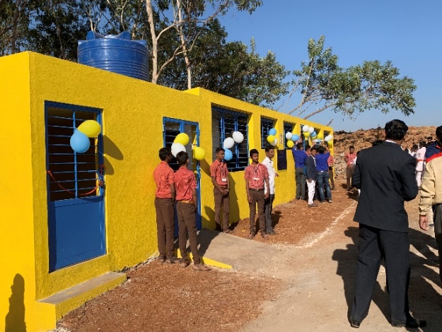 A group of people standing outside a yellow building

Description automatically generated with low confidence