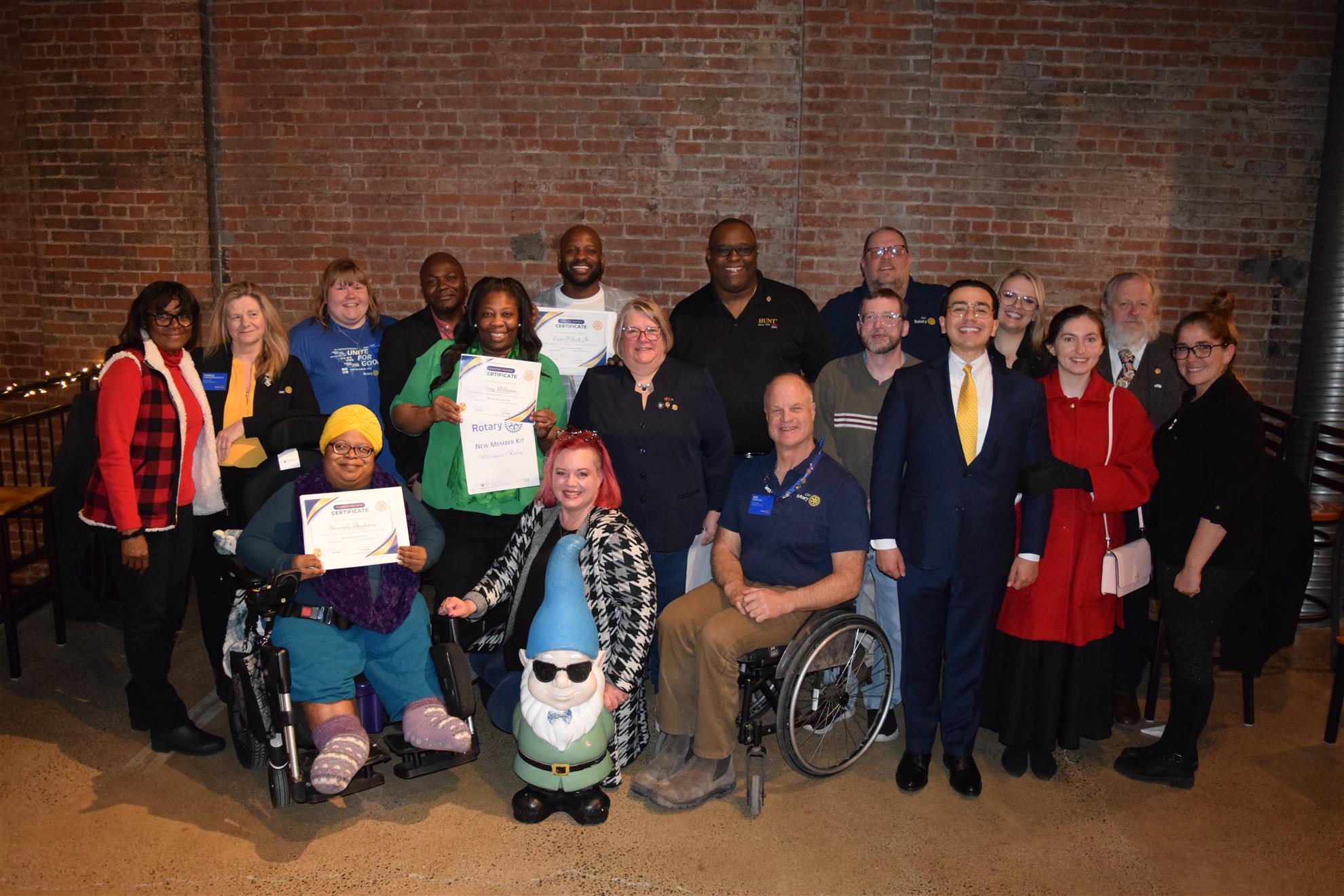 picture of a group of smiling people in front of a brick wall
