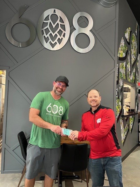 Owner Phil presents Eric with donation