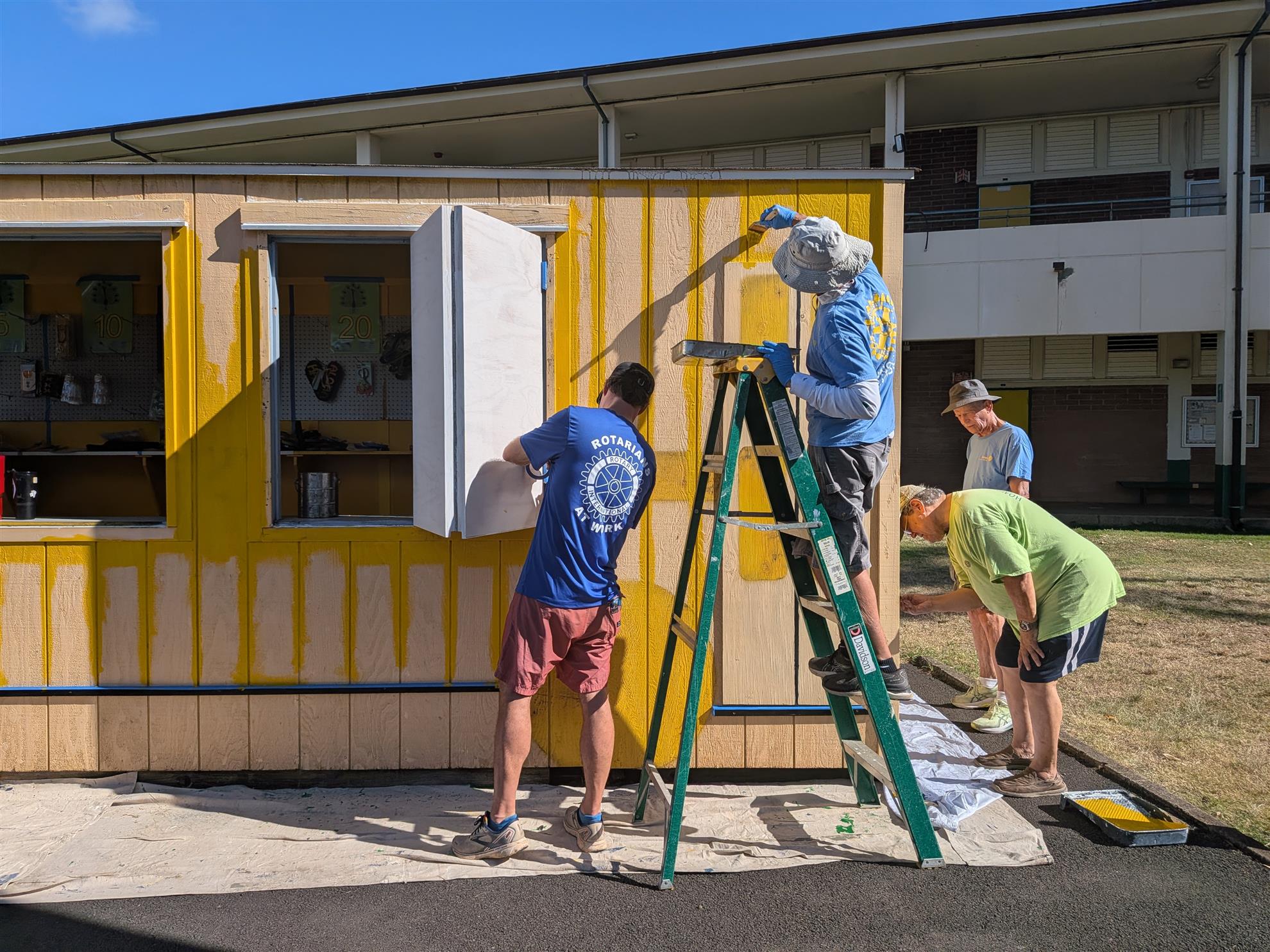 Volunteers painting the Peacock Bus around its open windows