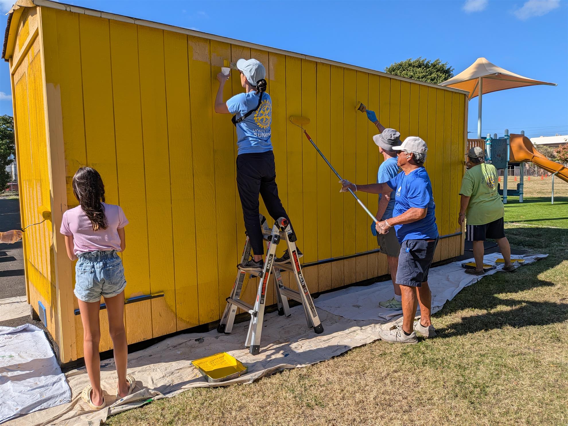 Volunteers using rollers and brushes on the yellow exterior