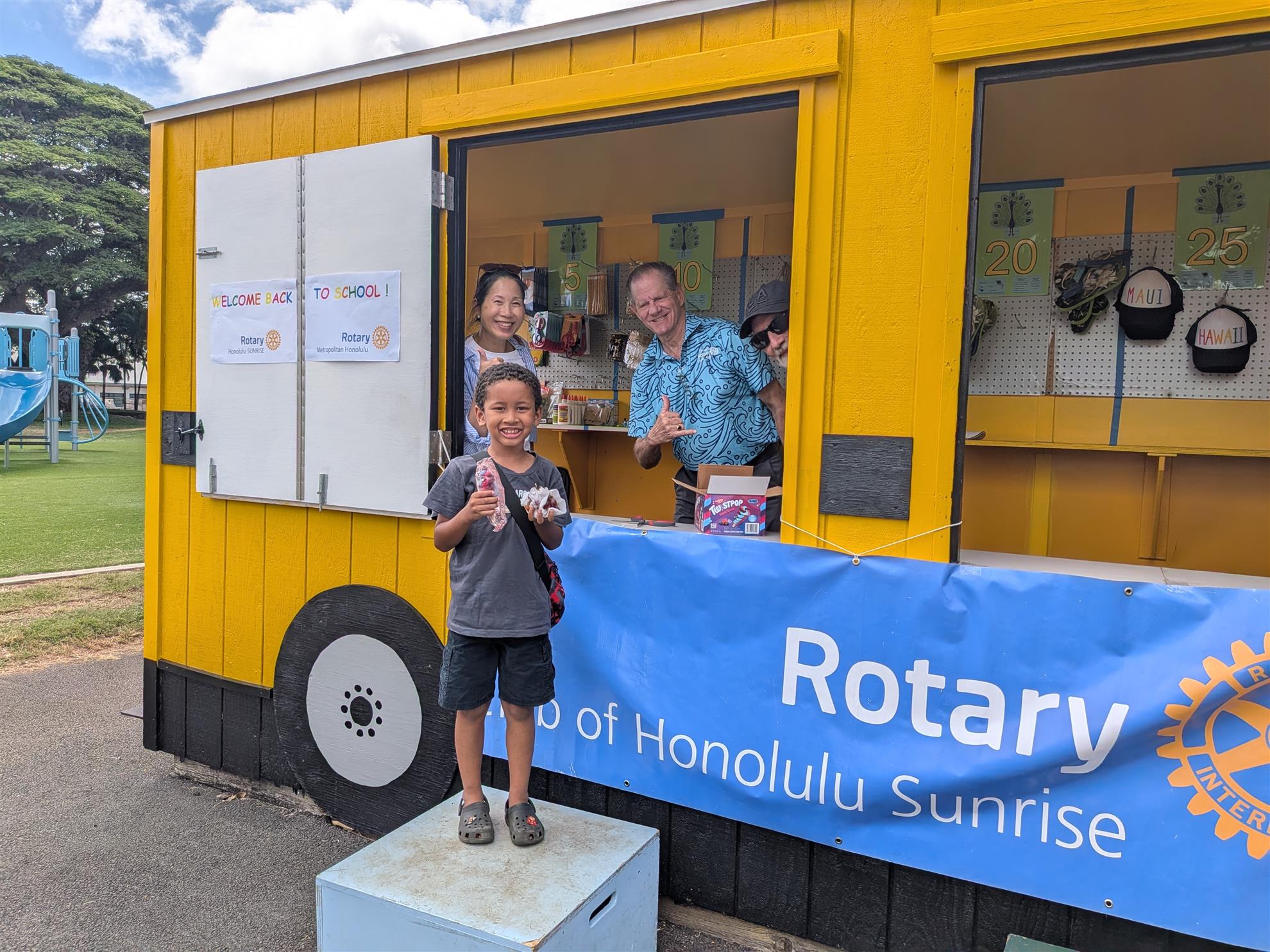 Visitors at the Peacock Bus beside a Honolulu Sunrise Rotary banner