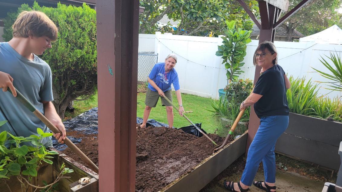 Volunteers planting and spreading soil in the planters