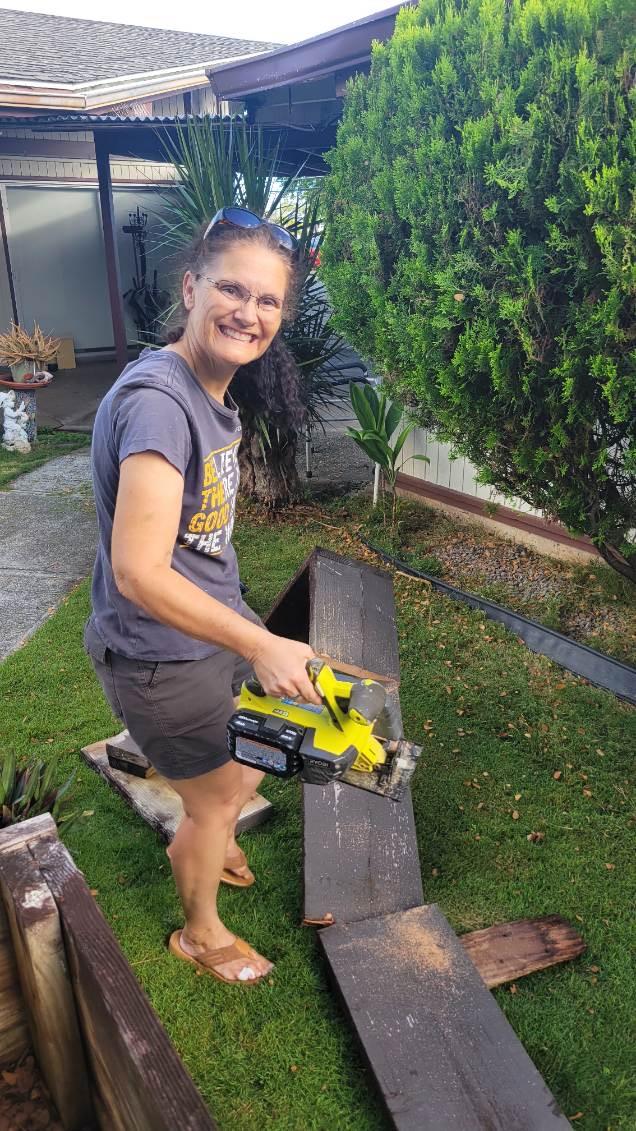 A volunteer cutting old boards with a power saw