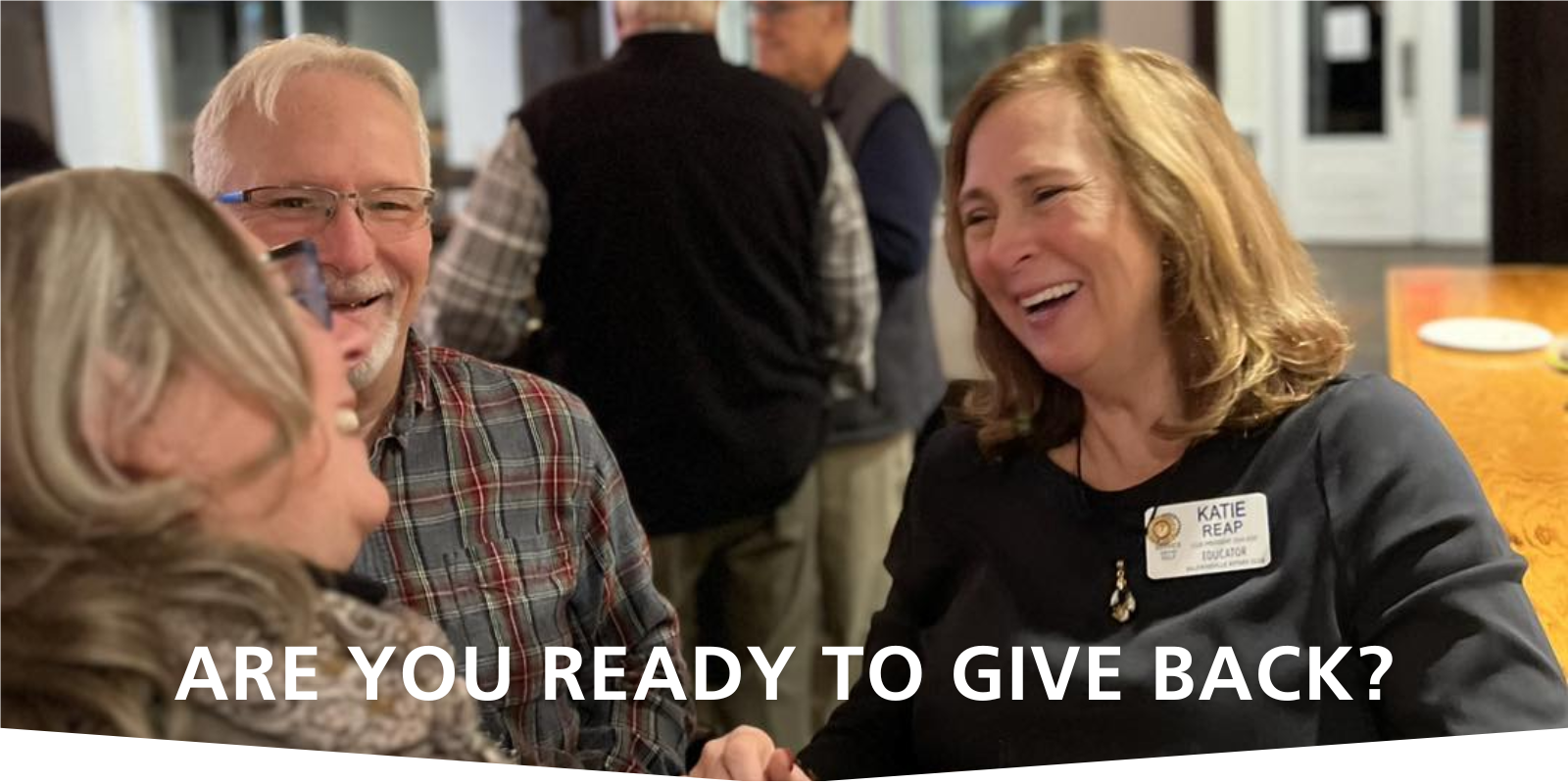 Two women and a man are interacting joyfully at a Baldwinsville Rotary event