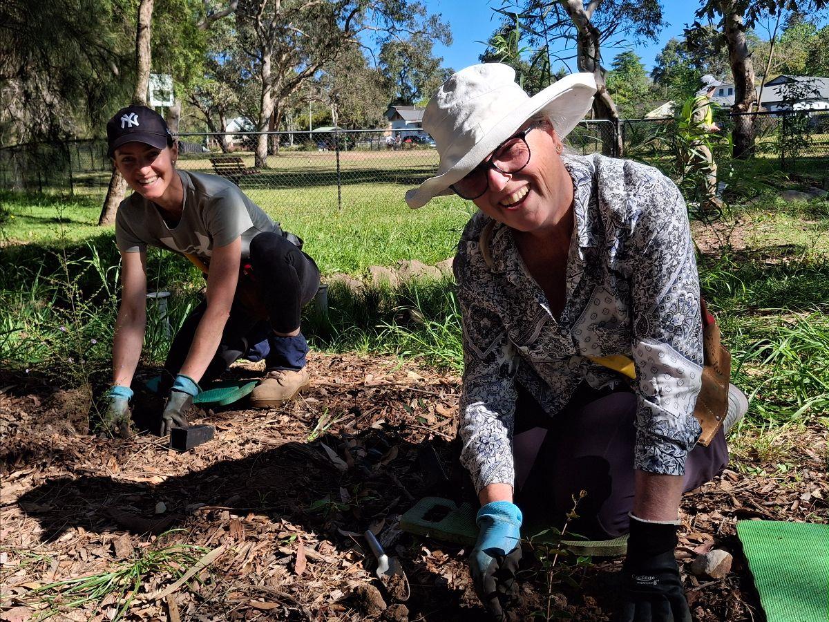 Two volunteers planting together and smiling