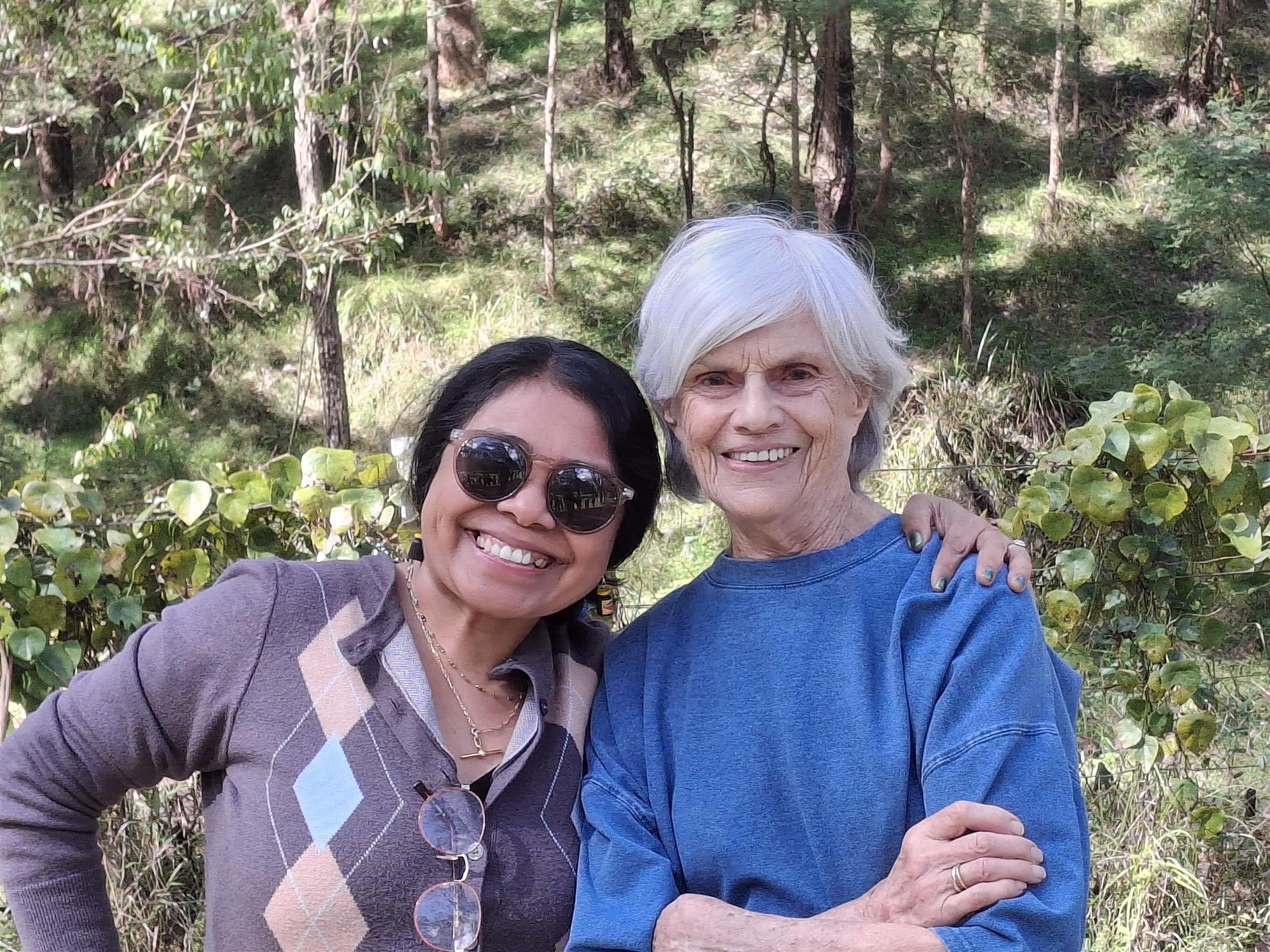 Two friends smiling with arms around each other in the bush