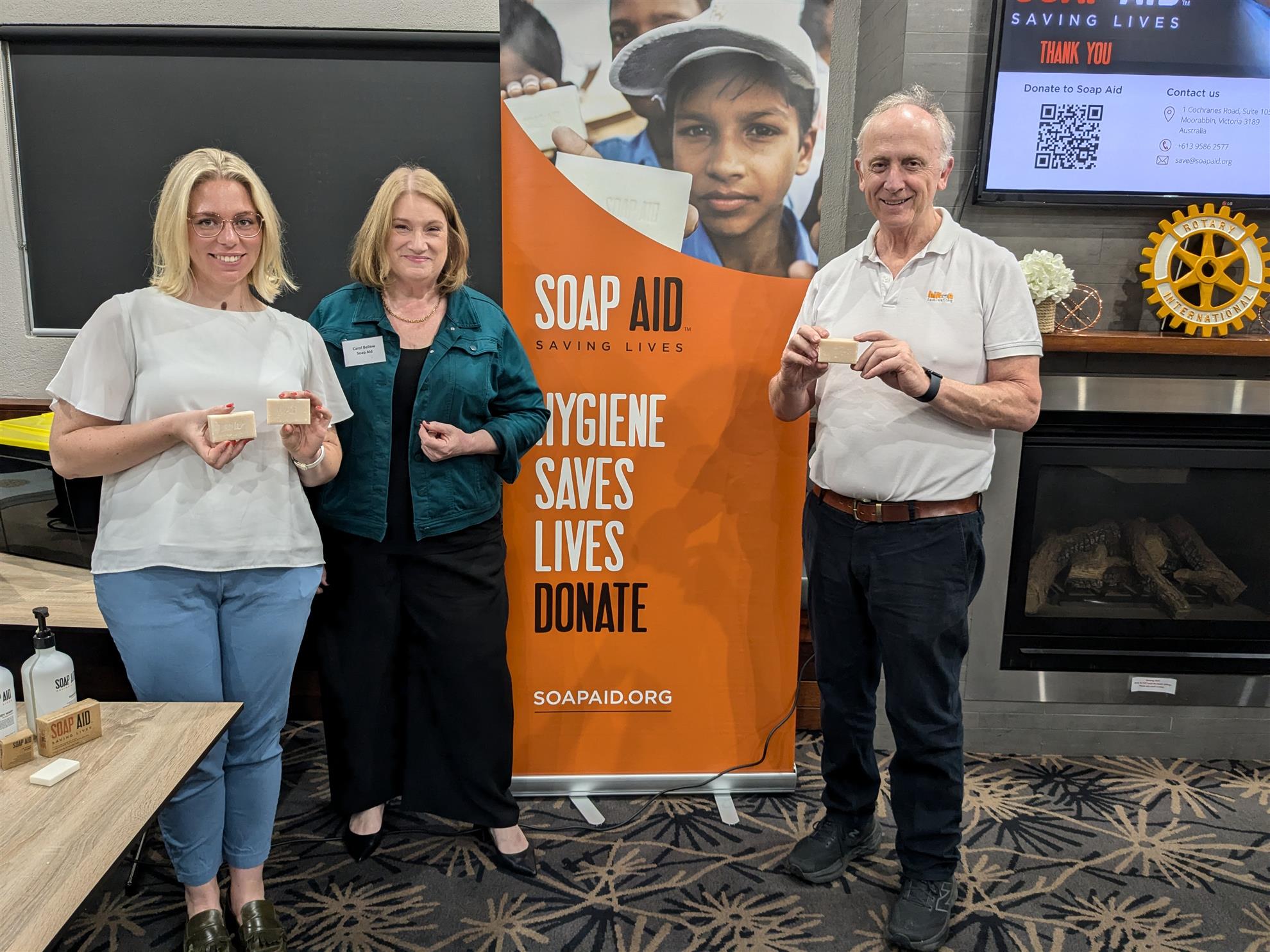 Sarah and Carol from SoapAid with John Peck holding recycled soap donated to vulnerable communities around the world
