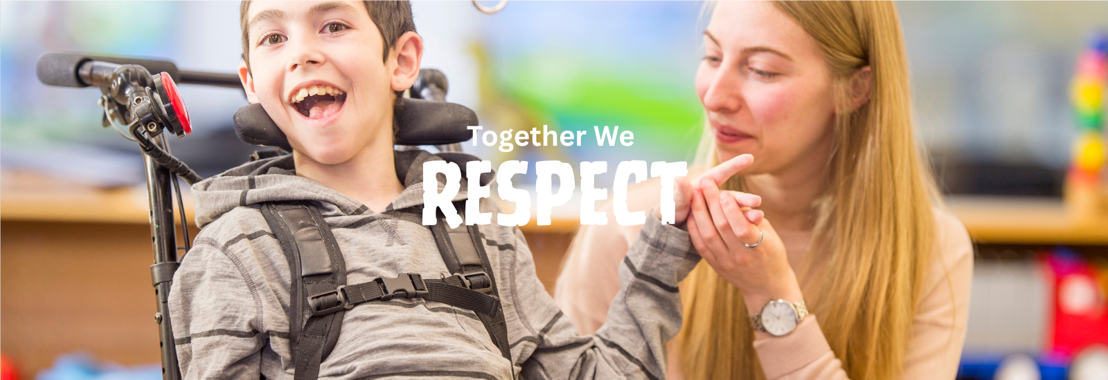 Smiling boy in a wheelchair holds an adult’s hand. “Together, We Respect.”