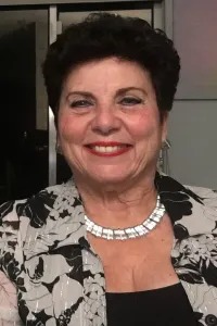 Portrait of Maureen Sinkule smiling and wearing a black and white floral jacket