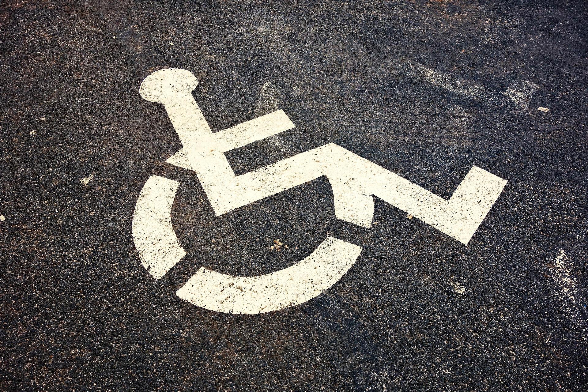 A close-up of a painted wheelchair symbol on asphalt, symbolizing the movement for accessible public transportation and inclusive mobility.