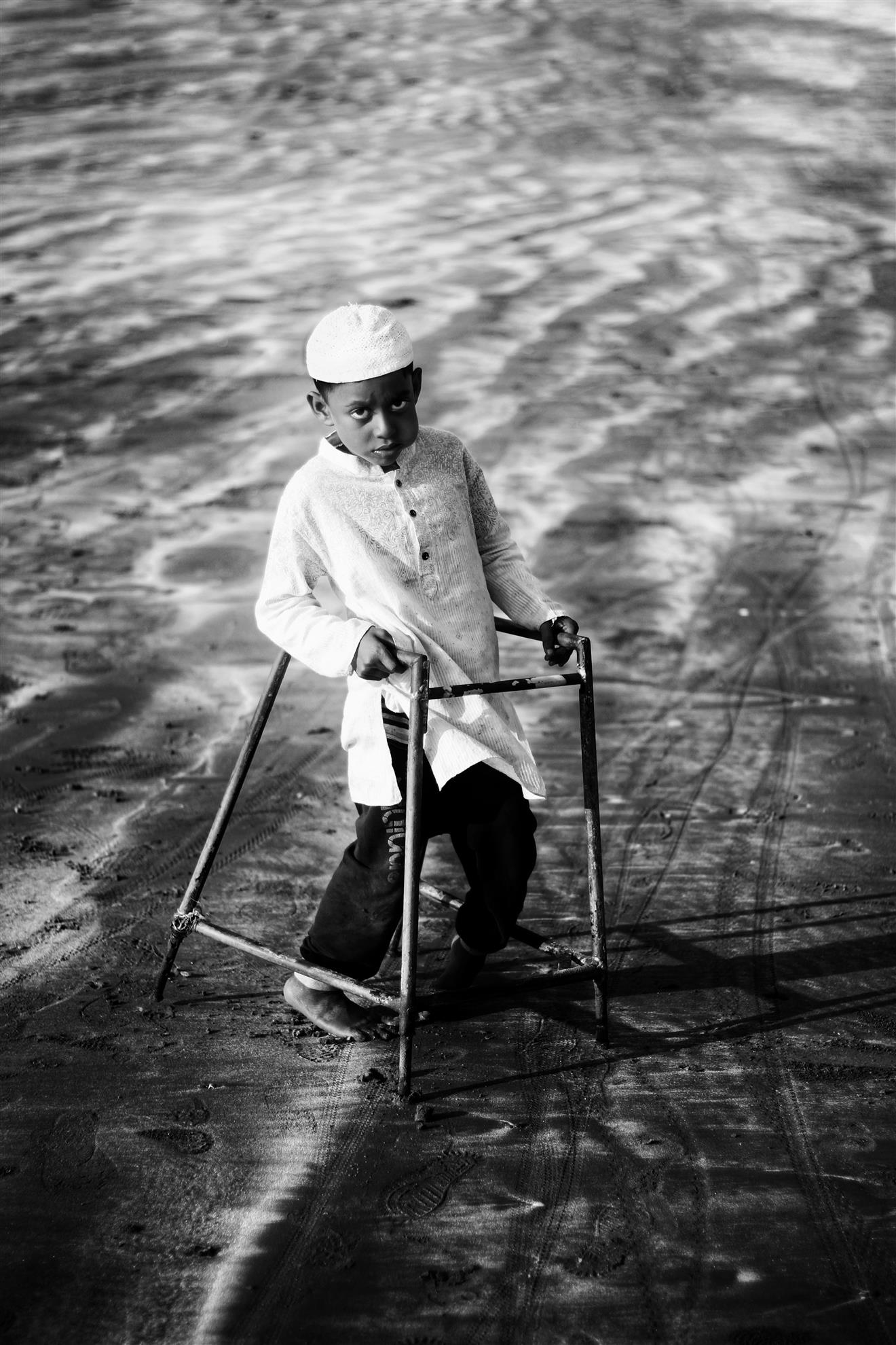 Historical black-and-white photograph of a child using a metal walking frame during polio rehabilitation.