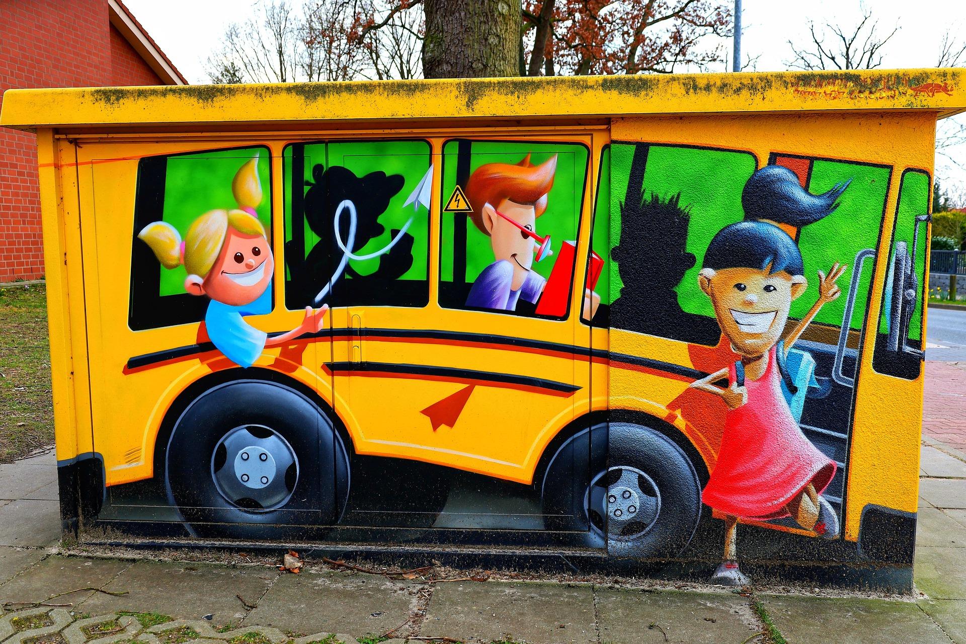 Illustrated mural of a bright yellow school bus with smiling children of different appearances inside and around the bus, symbolizing joy, diversity, and the daily journey to school.