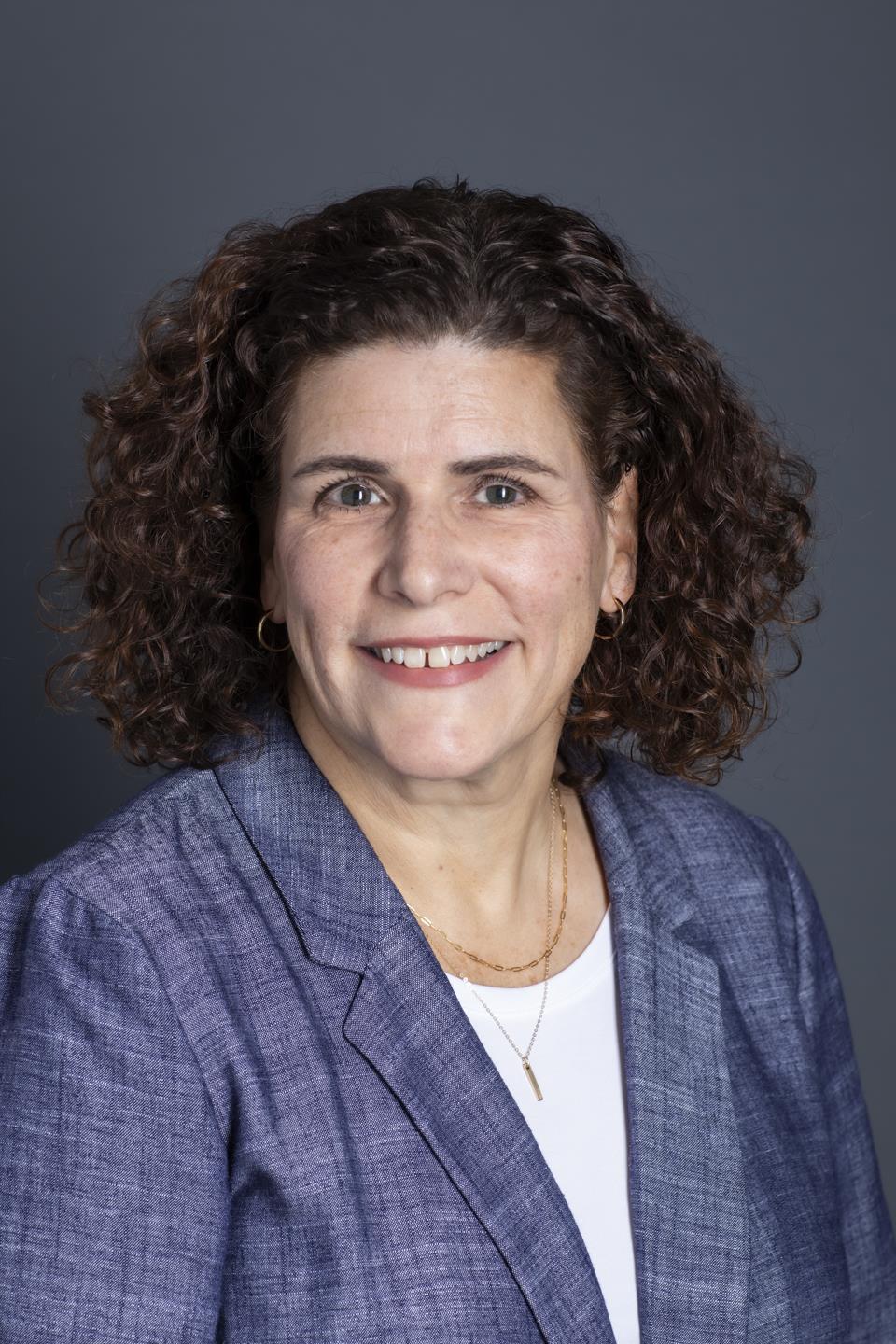 A person with curly hair wearing a blue blazerAI-generated content may be incorrect.