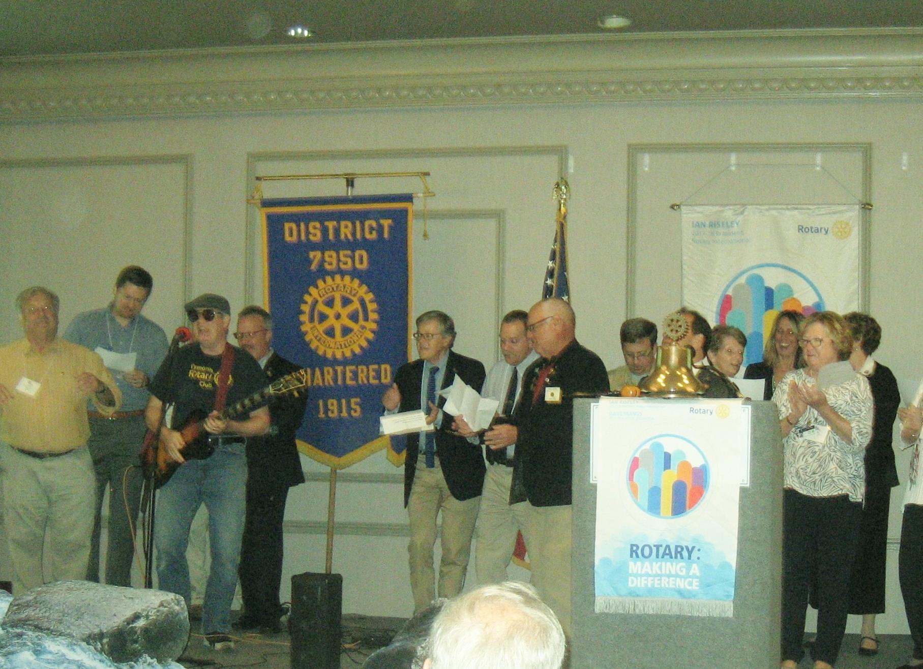 Dennis Carman leads Plymouth Rotarians in the Rotary version of We Will Rock You